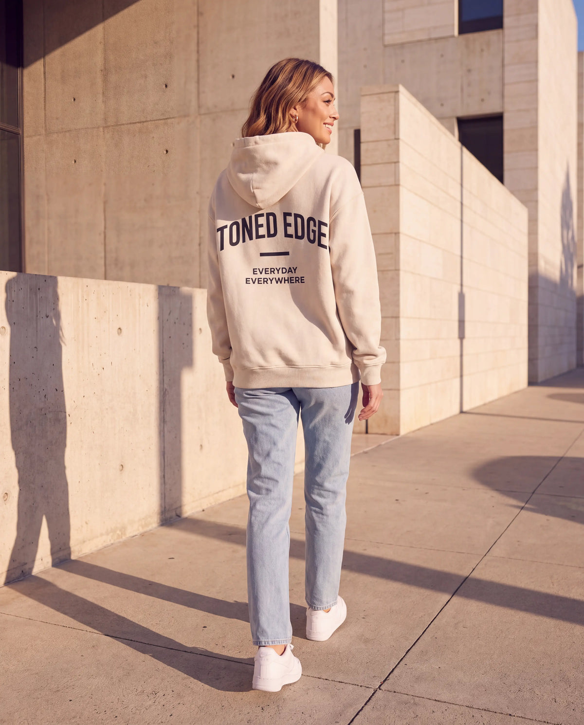 The Signature Hoodie in Bone, back view with arched Toned Edge print